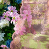 Pink and green vintage French-style lace curtain with a wave border draped over greenery.