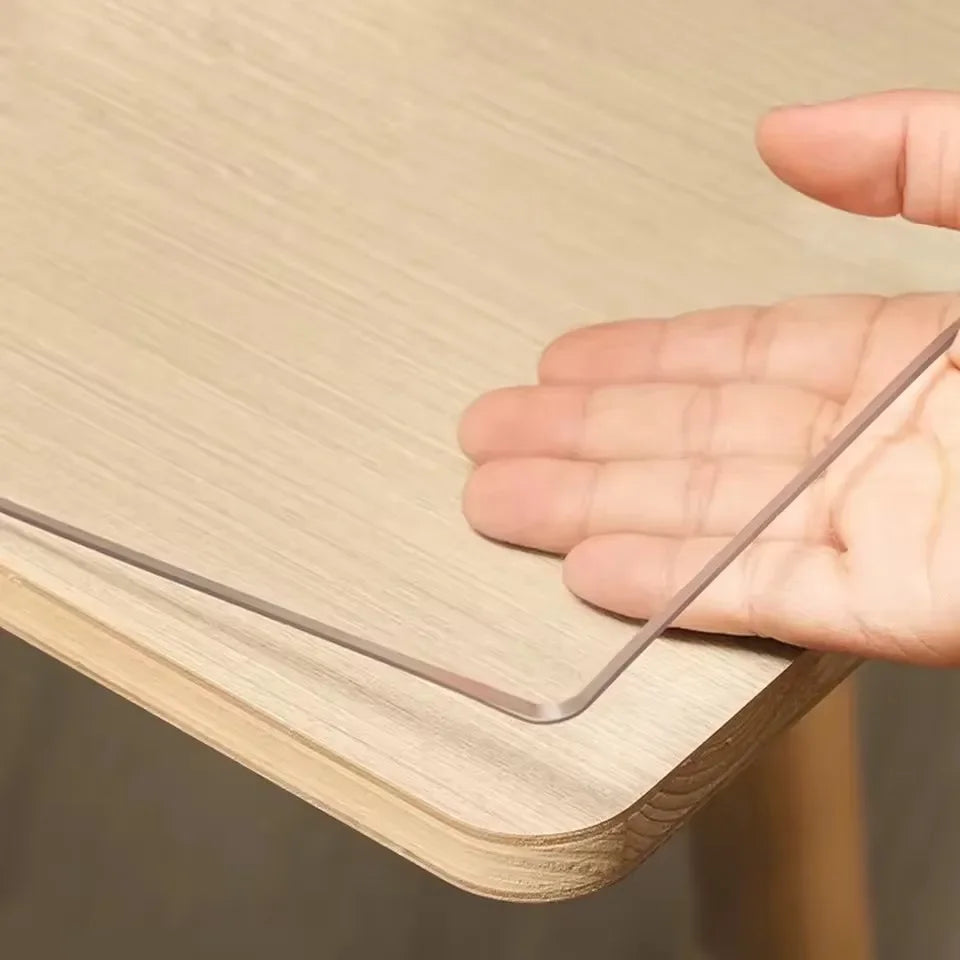A hand is placing a metal strip table protector mat onto a light wood surface.