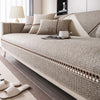 A beige linen sofa cover with decorative trim and pillows on a modern sofa in a living room.