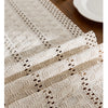 Beige boho hand-woven table runner featuring intricate lace patterns on a wooden surface.