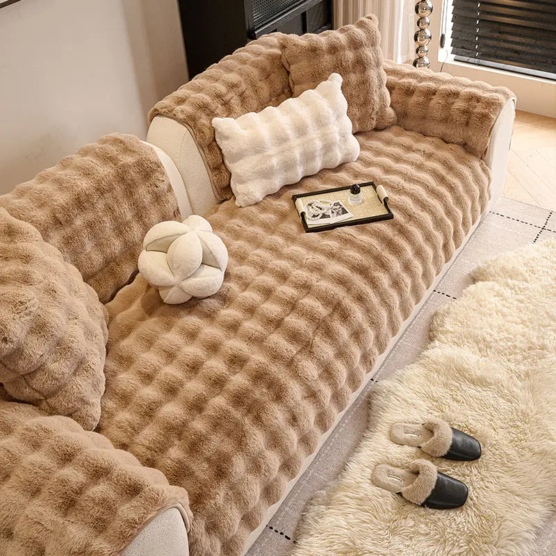 A plush, tan sofa cushion with textured fabric and decorative pillows rests on a light-colored floor.