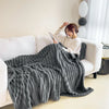 A woman is relaxing on a white sofa with a gray ultra-soft plush winter blanket draped over her.