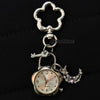Silver pocket watch keychain featuring a decorative heart-shaped charm and a small key.