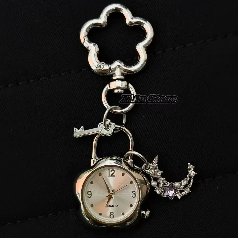 Silver pocket watch keychain featuring a decorative heart-shaped charm and a small key.