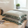 A set of two soft plaid washed cotton pillowcases with ruffled edges displayed on a table.