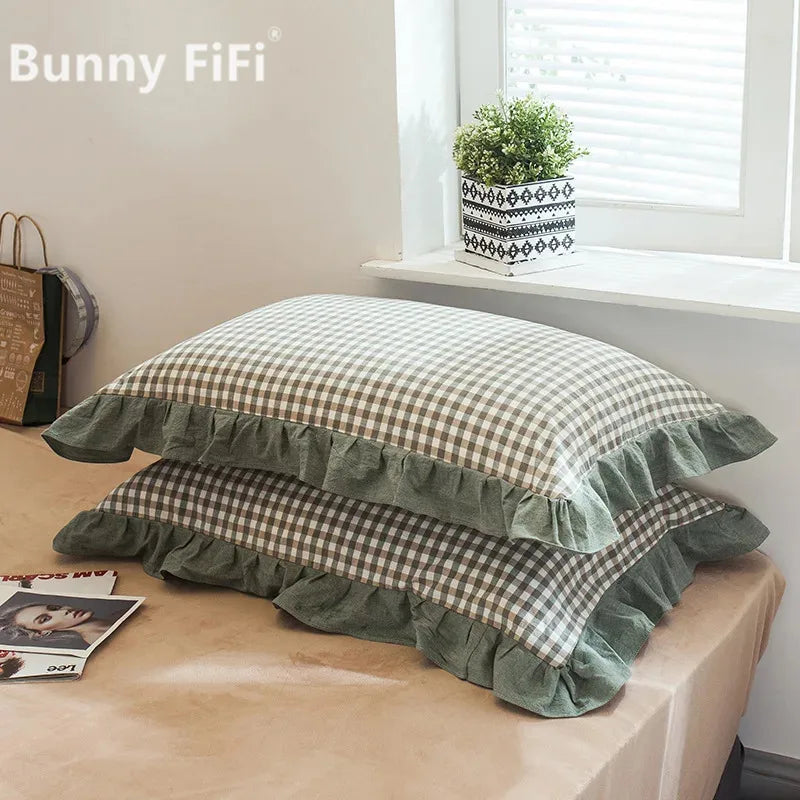A set of two soft plaid washed cotton pillowcases with ruffled edges displayed on a table.