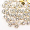 A close-up of gold and clear crystal rhinestone sew-on buttons arranged in a sunflower pattern.