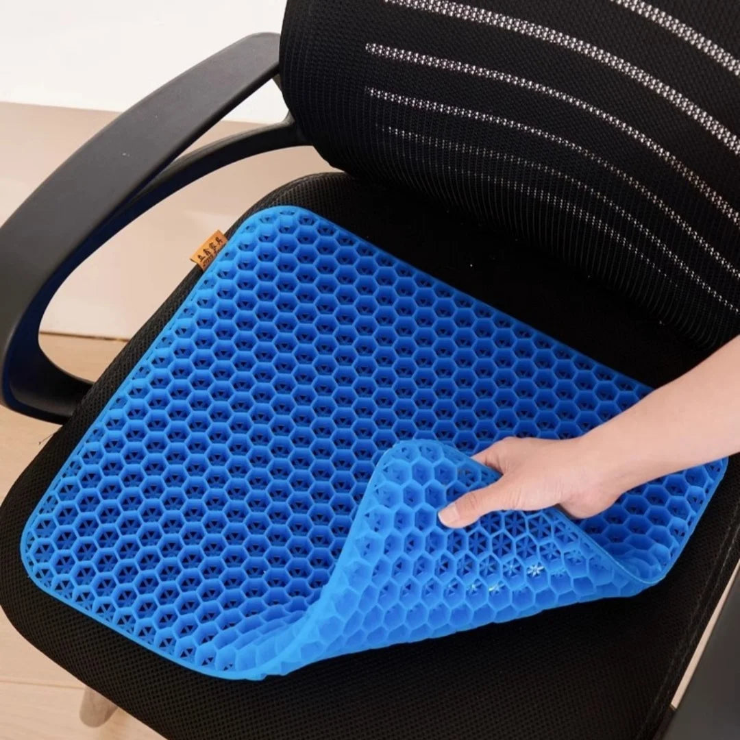 A hand is pressing a blue honeycomb silicone seat cushion into the seat of a black chair.