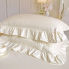 White lace ruffled bed skirt set with layered fabric and a decorative pillow
