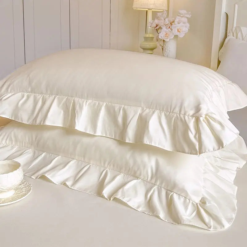 White lace ruffled bed skirt set with layered fabric and a decorative pillow
