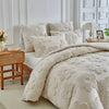 A beige 3D tufted floral duvet cover set with matching pillowcases displayed on a bed.