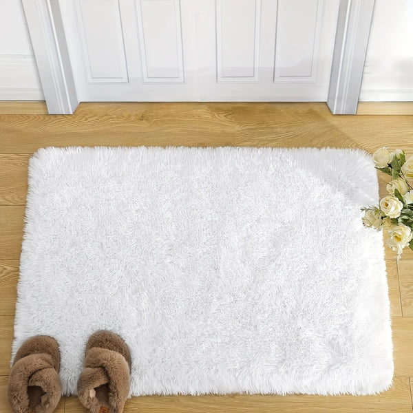 A fluffy white rug placed on a wooden floor with a white door frame in the background.