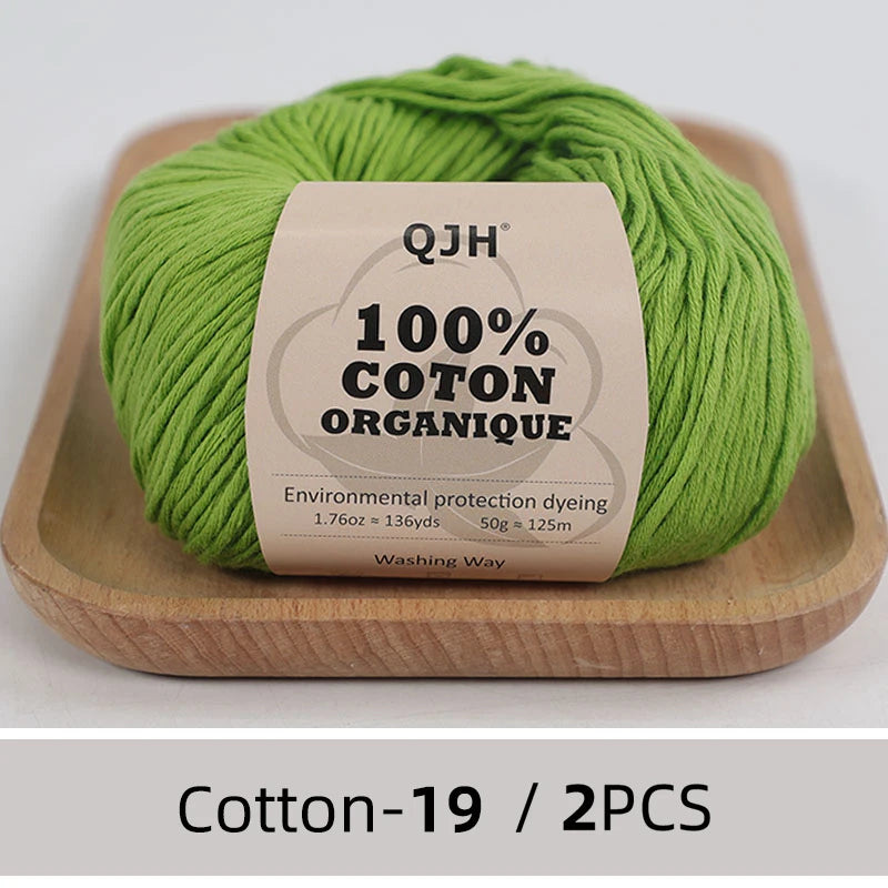 A ball of bright green 100% organic cotton yarn labeled QJH with environmental protection dyeing details.