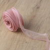 Pink wavy edge organza ribbon rolled and unwound on a wooden surface