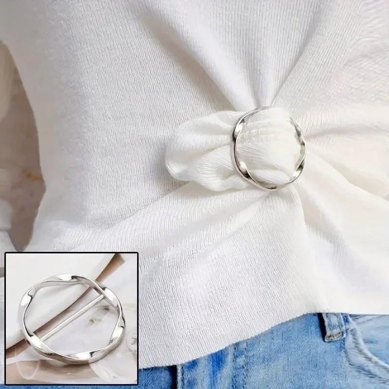Silver metal round clip buckle fastened on a white knitted sweater sleeve