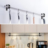 A silver curtain rod with multiple hooks is mounted on a white wall above kitchen cabinets.