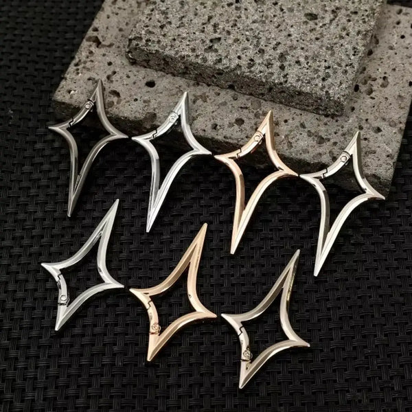 Silver alloy key ring buckles shaped like gothic Y2K stars resting on a dark textured surface.