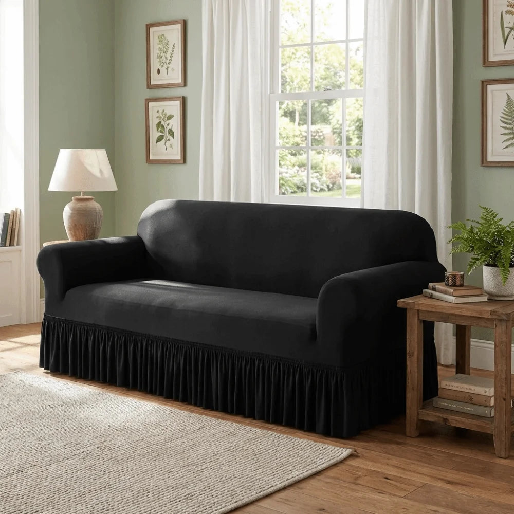 A dark gray dustproof stretch sofa slipcover placed in a light green room with natural light and wooden accents.