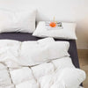 A set of three white plaid duvet covers and pillowcases displayed on a bed.