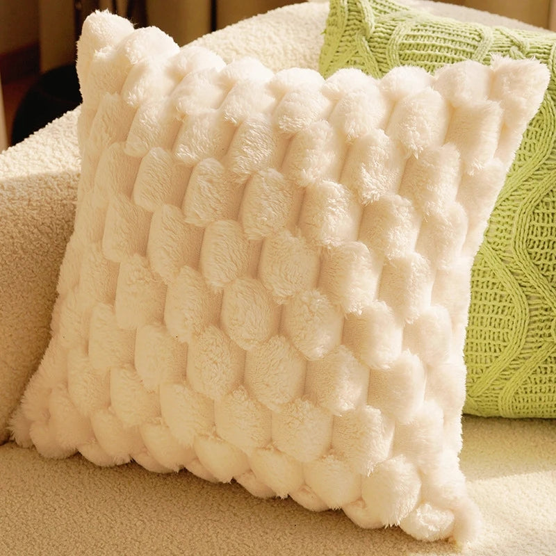 A square, white, textured plush pillow cover resting on a light-colored surface.