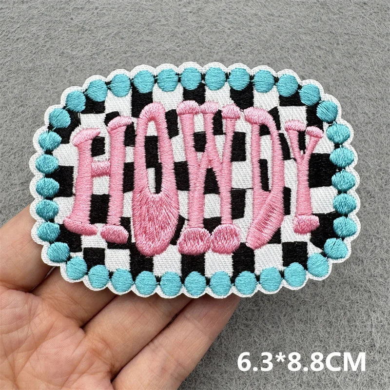 Pink embroidered slogan patch spelling HOWDY with a black and white checkered border