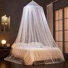 A sheer white dome mosquito net draped over a bed, providing protection.