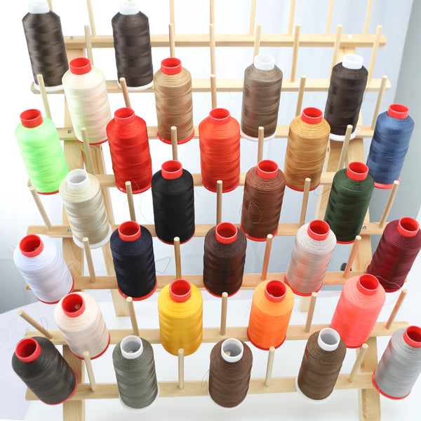 A collection of various colored heavy duty nylon sewing thread spools arranged on wooden sticks.