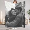 A personalized photo blanket featuring a black and white portrait of a man and woman embracing.