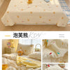 A yellow cartoon pattern lightweight summer quilt displayed on a bed with white bedding and accessories.