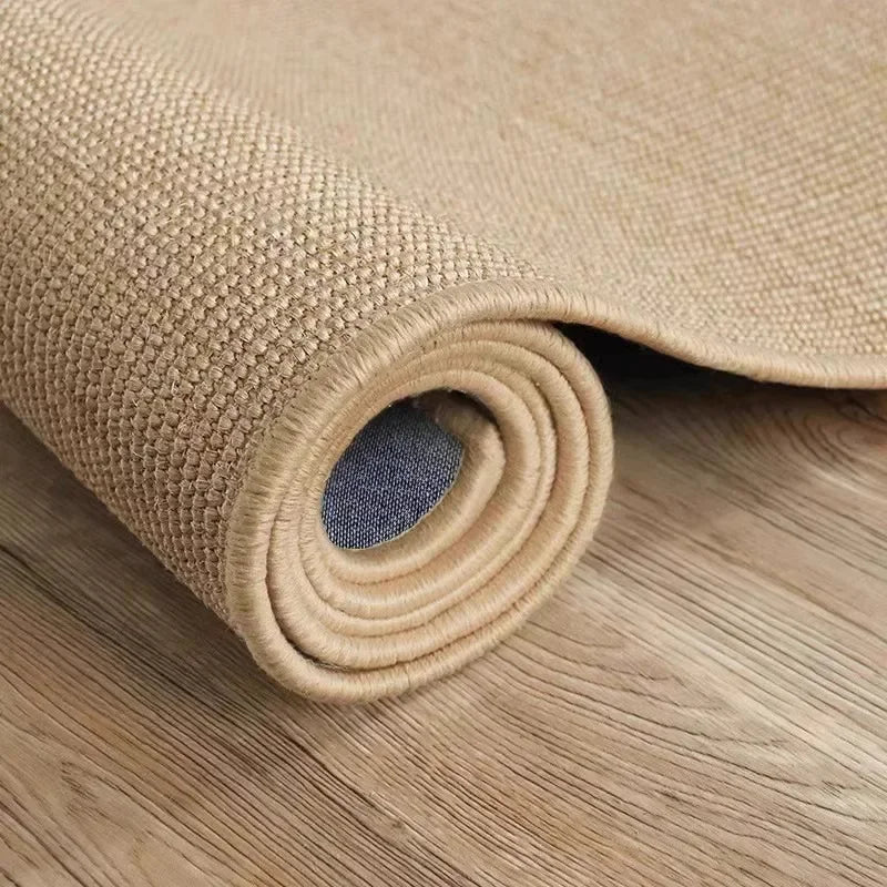 A rolled natural sisal jute rug in a light tan color resting on a wooden surface.