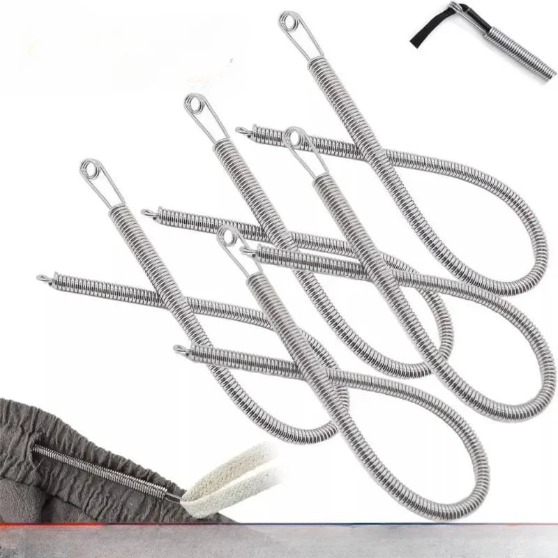 A set of silver spring drawstring sewing threaders lying on a gray fabric with a white cotton swab.