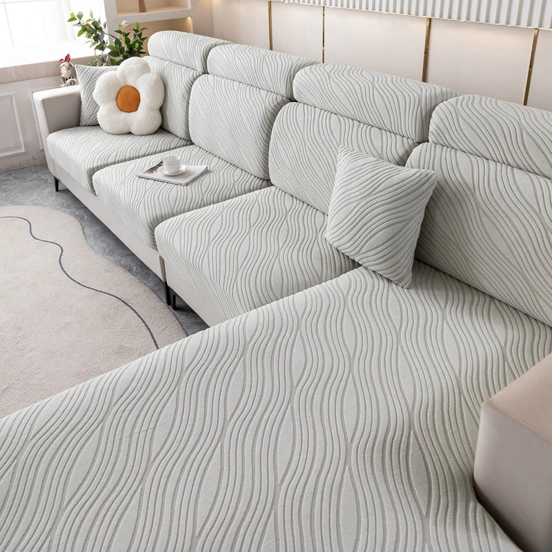A light gray plush elastic sofa cushion cover with a wavy texture is displayed on a modern sofa.