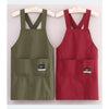 A pair of water-resistant kitchen aprons in olive green and maroon hanging on a wooden hanger.