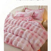 A pink and white checkered plush rabbit quilt comforter draped on a bed.