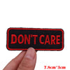 Black embroidered patch with the text DON'T CARE on a finger