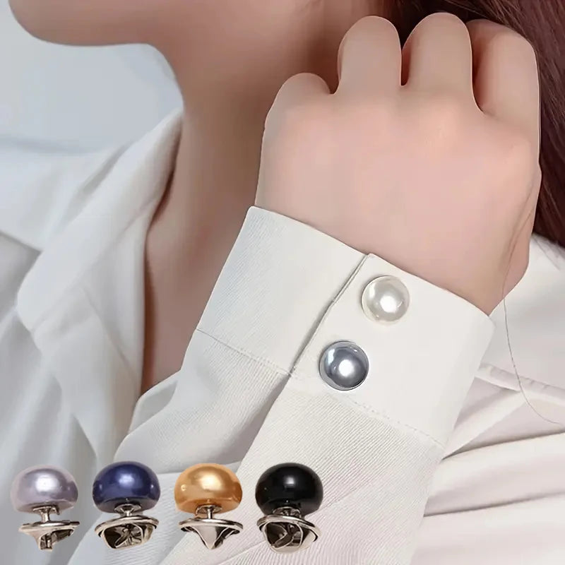 A close-up of pearl button pins in various colors and finishes being held by a hand against a white shirt.