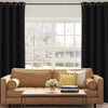 A living room features a beige sofa, wooden table, and large window covered by black blackout thermal drapes.
