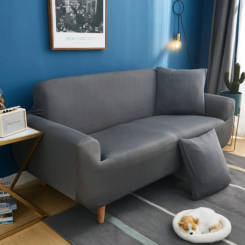 A modern gray universal stretch sofa and chair slipcover placed in a living room setting.