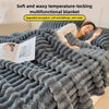 A gray fluffy blanket is shown being used by a woman sleeping comfortably.