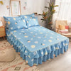 A light blue printed bed skirt with ruffled edges and pillows on a bed.