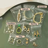 Clear plastic storage bags containing various jewelry items like earrings, necklaces, rings, and bracelets