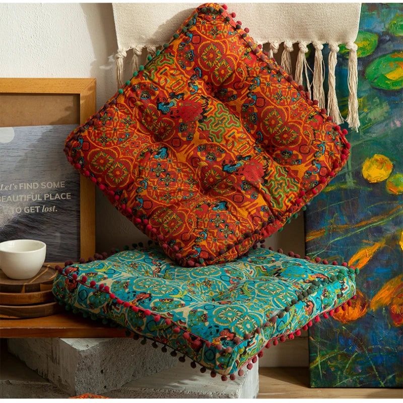 A vibrant orange and red bohemian cotton linen throw cushion resting on a wooden shelf.