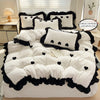 A white duvet set with black embroidered hearts and piping displayed on a bed.