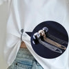A close-up of a black circular inset showing gold and silver chains, used as a detail on a white shirt.