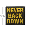 Black embroidered patch with gold text reading NEVER BACK DOWN