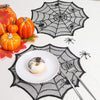 A festive autumn display featuring pumpkins, a white donut, and a black spider web design on a white surface.