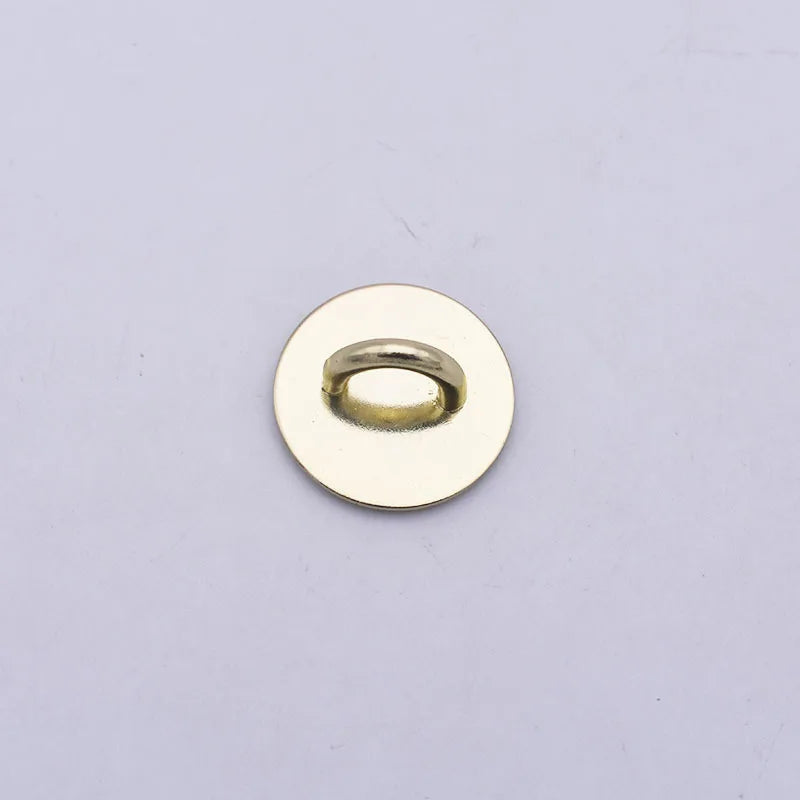 A round, gold-colored metal connector or charm with a central ring.