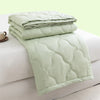 A light green quilted duvet folded on a white surface.