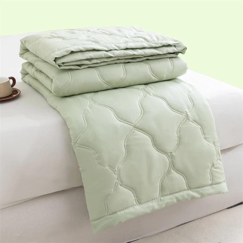 A light green quilted duvet folded on a white surface.