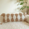 A beige knit pillow cover with a geometric pattern in brown tones rests on a light-colored sofa.